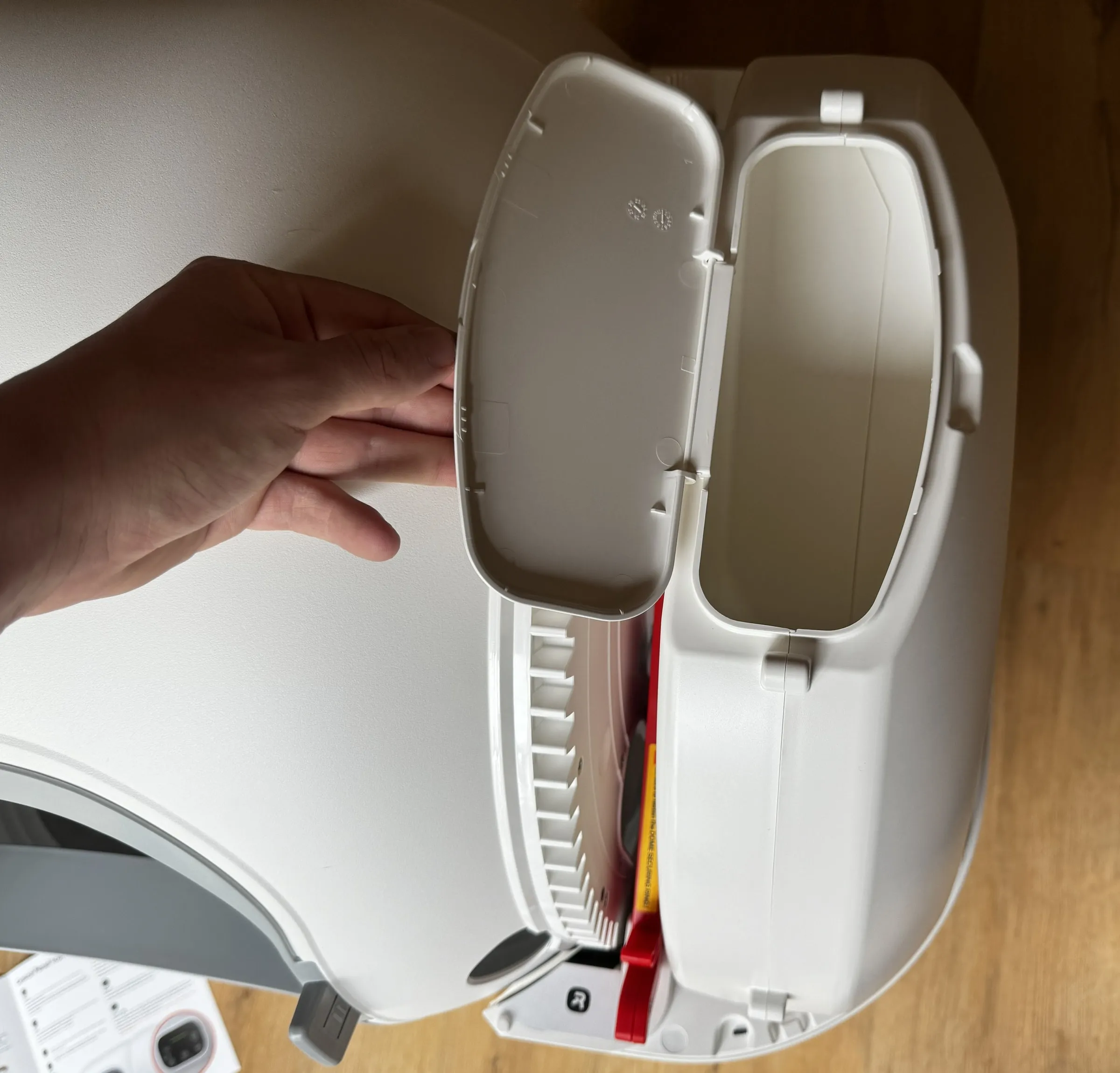Open auto-refill reservoir on the mounted homerunPET CS106, with the lid lifted by hand and the front entry visible below