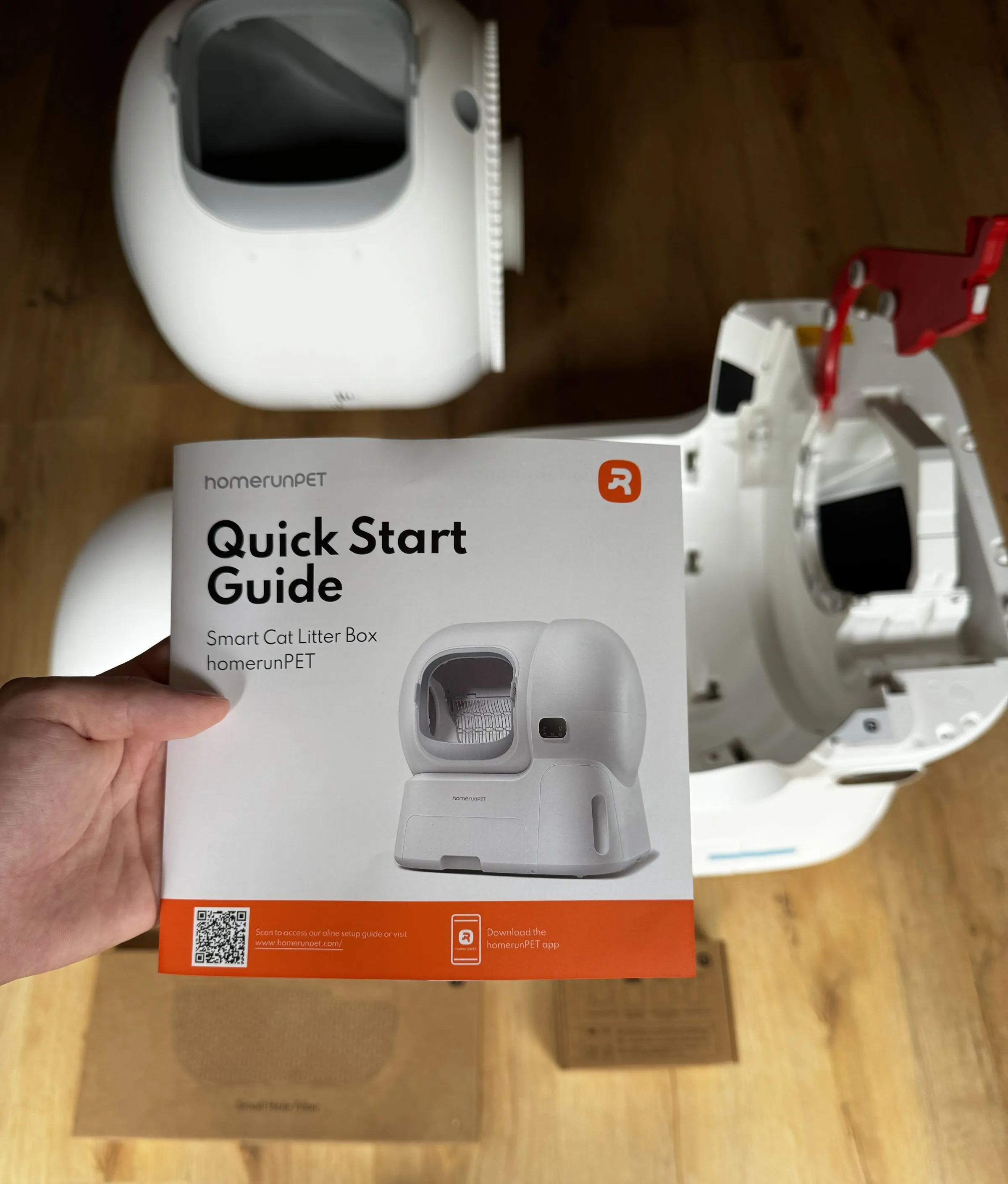 homerunPET CS106 quick start guide held in front of the unboxed and partly disassembled litter box during setup